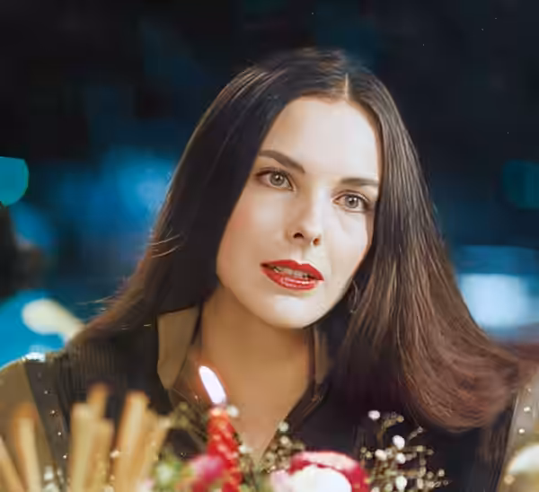 Carole Bouquet à table sur la terrasse d'un restaurant, la nuit, lors des fêtes de fin d'années. Elle porte ses cheveux longs noirs et lisses avec la raie au mi (1982)