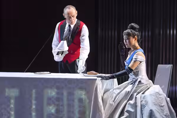 Production of Lear at Hamburgische Staatsoper 2012, stage photo: Ha Young Lee as Cordelia (on chair, right), Erwin Leder as the Fool (standing, center).
