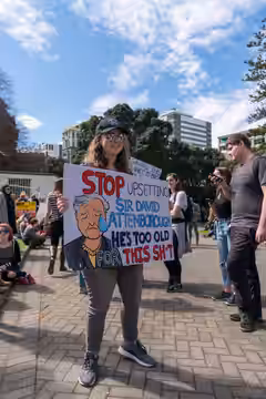 Artist and student Ashley McDonald protests at Parliament with a sign "Stop upsetting Sir David Attenborough - he's too old for this shit" Strike 4 Climate marc (2019)