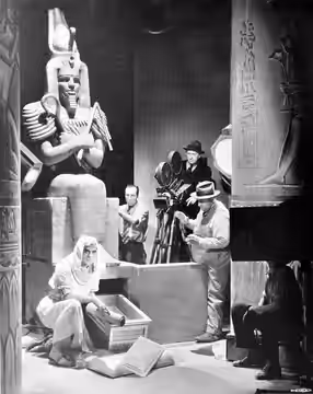 Photograph of Karl Freund directing Boris Karloff on the set of The Mummy (1932). Caption reads as follows:Here is Karl Freund, long time cameraman and now dire
