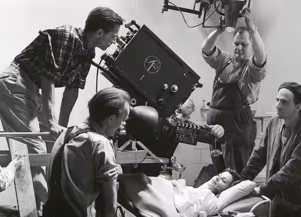 Filmfotograf Gunnar Fischer (bakom kameran) under inspelningen för "Kvinnors väntan", till höger Ingmar Bergman och på sängen Maj Britt Nilsson. (1952)