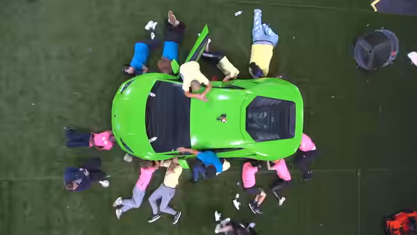 Overhead shot of a green Lamborghini. Many people are putting their hands on the Lamborghini. (2022)