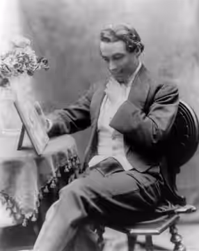 Henry B. Walthall, three-quarters length, seated on chair, facing left, hand under chin, looking at picture (1911)