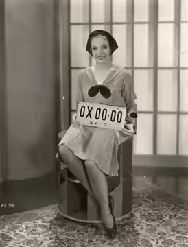 Film actress Sally Blane. From the back: "New York notorists will have black letters and numerals against a background of yellow of their 1931 license plates, a (1930)