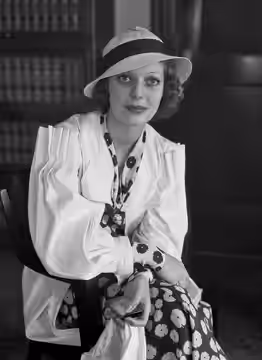 Loretta Young sits in a chair in what appears to be an office.