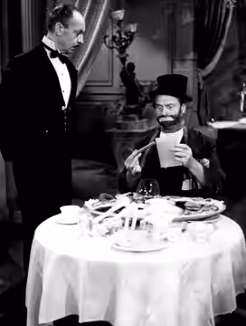 Photo of Red Skelton as Freddie the Freeloader. Maurice Marsac, as the waiter, has just brought Freddie the bill for his fine meal at a posh restaurant on The R (1954)