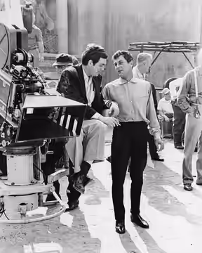 Production photo of director Stanley Kubrick (left, seated) and actor Tony Curtis (right) on the set of the 1960 film Spartacus.
