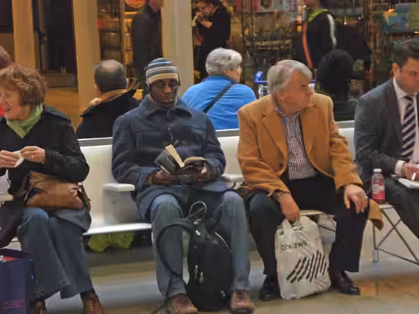 Some passengers waiting at at St Pancras International. Actor Paterson Joseph is second from the left, reading his book. (2008)