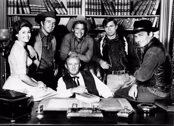 Cast photo from the television program The Virginian. Center: Lee J. Cobb (Judge Garth). From left: Roberta Shore (Betsy Garth), Clu Gulager (Emmett Ryker), Dou