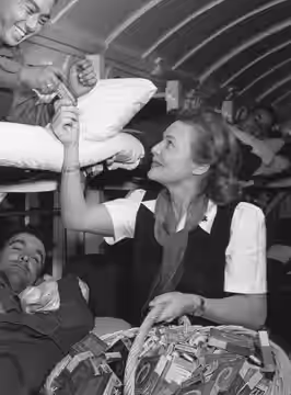PFC Hiroshi Suyaoka, of Honolulu, a Japanese American soldier, wounded during an attack, receives a Hershey bar from Madeleine Carroll, the actress. Miss Carrol (1944)