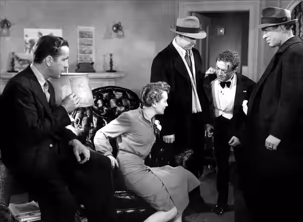 Promotional still from the 1941 film The Maltese Falcon, published on page 12 of National Board of Review Magazine. L-R: Humphrey Bogart, Mary Astor, Barton Mac