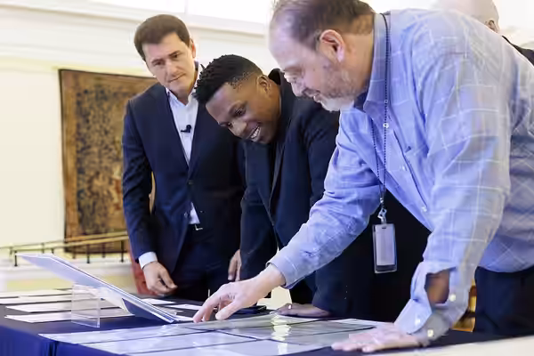 Ken Biberaj, left, and Leslie Odom Jr., center, look over a special collections display with curator Mark Horowitz in the Whittall Pavilion, November 13, 2024. 