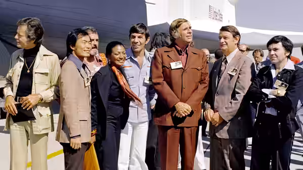 The Space Shuttle Enterprise rolls out of the Palmdale manufacturing facilities with Star Trek television cast and crew members. From left to right: DeForest Ke