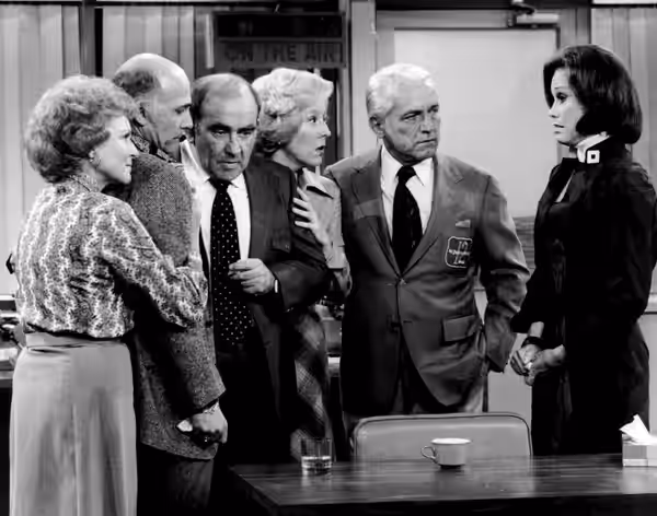 Cast photo from the television program The Mary Tyler Moore Show. After the news that most of the WJM-TV staff has been fired, everyone gathers in the newsroom. (1977)