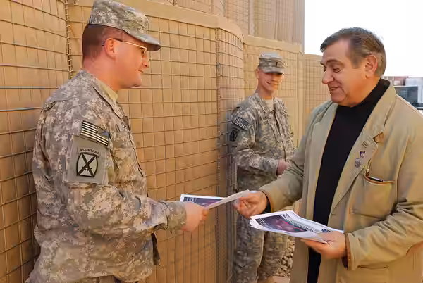 Hollywood actor Dan Lauria hands an autographed photo to Staff Sgt. Brian Cull, Headquarters and Headquarters Company, 10th Combat Aviation Brigade, Dec. 25, as (2008)