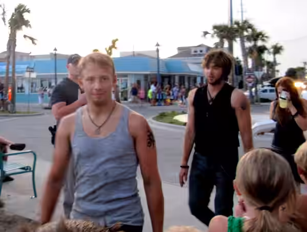A crowd watches as Adam Barnett, Nick Lashaway, and Carly Chaikin walk toward the Tybee Island pavillion, where the bonfire scene took place.