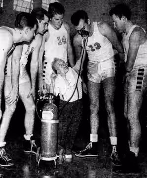 American actor Billy Barty (center foreground) lifts an oxygen mask up to Los Angeles City College basketball player Dick Green (center right, number 13) as his (1951)