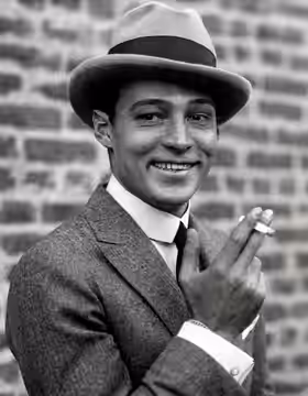 Omschrijving: Filmster Rudolf Valentino rookt een sigaret, Verenigde Staten jaren '20.