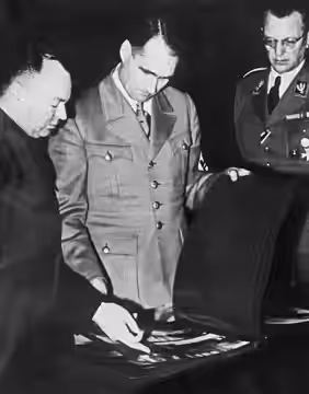 Ir. Anton Mussert brengt verslag uit in Munchen bij Rudolf Hess (m) en laat Hess foto's zien van de Nederlandse situatie. ANP/Anp. 20-04-1941.