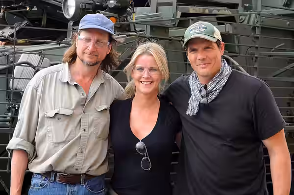 Don McManus, Maeve Quinlan and Paul Johansson stand next to a Stryker armored combat vehicle outside a battle damage repair facility at Camp As Sayliyah, Qatar, (2009)