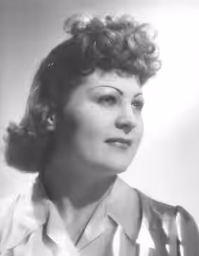 Dominique Davray pose la tête orientée vers sa gauche et le regard dans la même direction, vers le haut esquissant un très léger sourire. Elle porte les cheveux (1950)