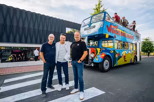 From left: Dave Kirby, Alexander Pietschmann, and Markus Jahnel in front of the restored Wings tour bus during the 50th anniversary celebration of the Adam Hall (2025)