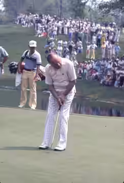 A view of actor and comedian Bob Hope putting a ball during the 1977 Memorial Tournament pro-am at the Muirfield Village Golf Club. A caddie stands off the gree
