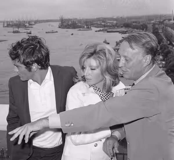 "Modesty Blaise" film van Amerikaan Joseph Losey. Filmopnamen te Amsterdam. Monica Vitti te midden van tegenspeler Terence Stamp en regisseur Joseph Losey (1965)