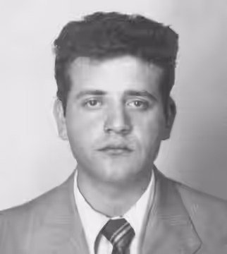 Jean Yanne coiffé en brosse, cheveux bruns épais et ondulés, regarde l'objectif sans émotion particulière. Il est vêtu d'un veston gris clair, d'une chemise bla (1955)