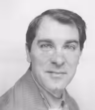 Jean Poiret, buste tourné vers la gauche, tourne la tête vers sa droite, regardant l'objectif, sans émotion notable. Il est vâtu d'un blouson en tissus gris et  (1959)