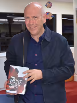 Australian author Richard Flanagan with a copy of his 2013 novel The Narrow Road to the Deep North, at Mosman Library, Sydney in October 2013. Other information