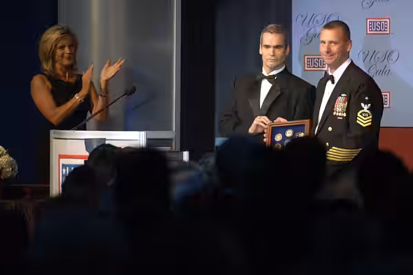 Local personality Henry Rollins, center, presented Navy Chief Petty Officer James P. Moran, right, with the United Service Organizations' 2005 Sailor of the Yea