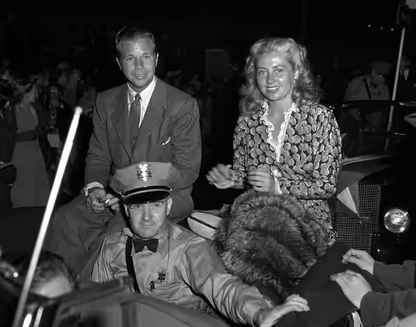 Celebrities Dick Powell and Joan Blondell riding in a car for the Moon Festival parade, going through Chinatown in Los Angeles. (1941)