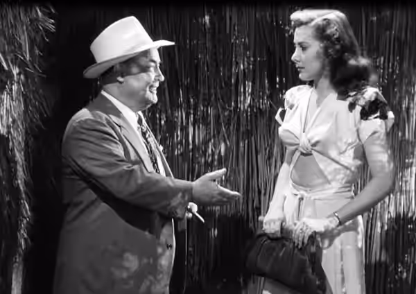 Low resolution screenshot of Dick Elliott as P.T. Burke and Gloria Warren as Rona Simmonds from the American film Dangerous Money (1946). Burke is demanding mon