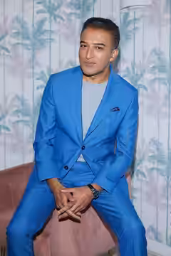 A full length photograph of Adil Ray, taken by Ian Wallman. Copyright of Adil Ray. (2023)