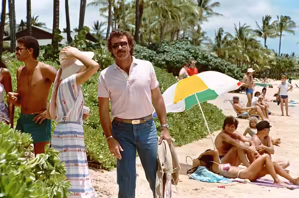 Tom Selleck, filming a scene for MAGNUM P.I. in April 1984 at the Kahala Hilton Hotel in Hawaii. The woman standing next to him, in sriped dress, is Sharon Ston (2010)