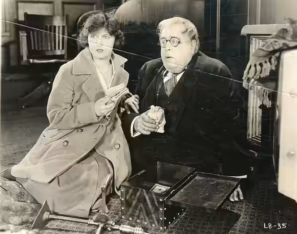 A scene from the American film Cheating Herself (1919) with Peggy Hyland and S. Z. Sakall. Date stamped Aug. 3, 1919. From the back: "It is difficult to associa