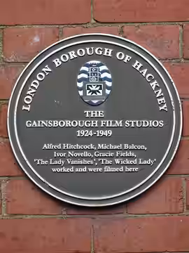Brown plaque erected by the London Borough of Hackney at the site of Gainsborough Film Studios, Poole St, Hoxton, London N1 5EE. The plaque states that “The Wic (2021)