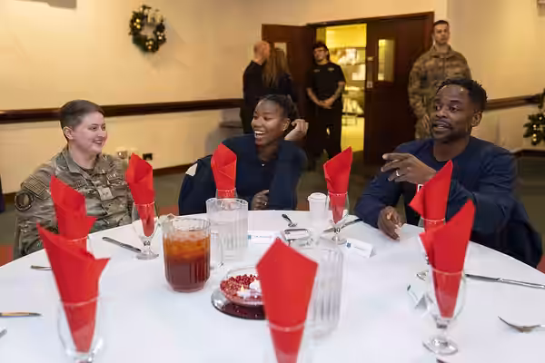 Actor Dulé Hill and his daughter sits down for a meal with U.S. Airmen during the 2023 USO Holidays Tour at RAF Lakenheath, December 11, 2023. For 82 years, the