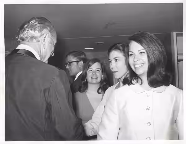 Black and white photograph print of Lyndon B. Johnson shaking hands with an unidentified woman.