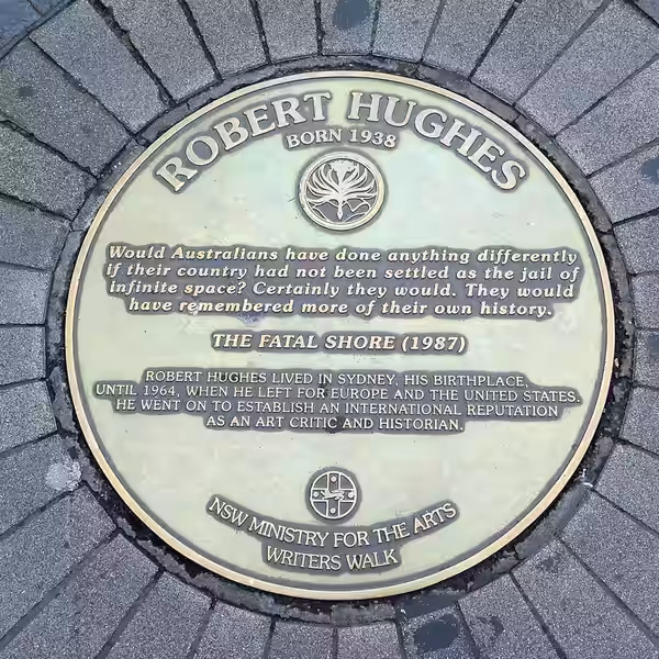 A metal plaque set in the sidewalk at Circular Quay in Sydney commemorating author Robert Hughes as part of the Sydney Writers Walk series (2019)