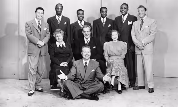 Photo from promotional postcard for Red Skelton's Raleigh Cigarettes radio show. Standing: Pat McGeehan, The Four Knights, David Rose (orchestra leader). Seated