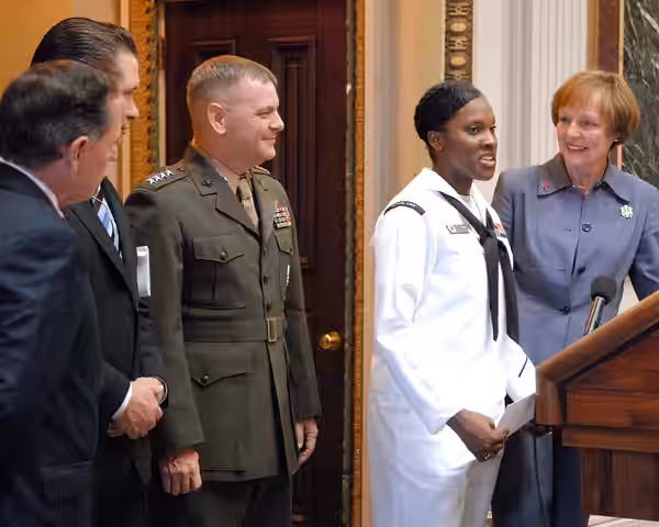 U.S. Navy Petty Officer 1st Class Haneefah Collins, in dress white, speaks to the audience at the USA Freedom Corps President's Volunteer Service Awards present