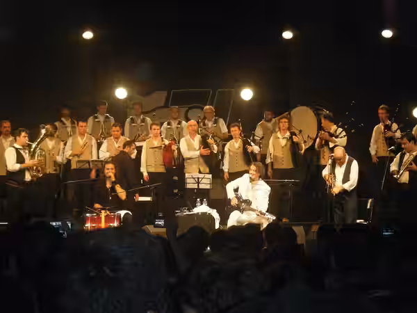 Goran Bregovic (in white) and the Wedding and Funeral Orchestra with the Saint-Malo's bagad (back of the scene, in white) during the Interceltic festival of Lor (2009)