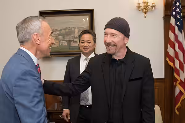 U.S. Department of Agriculture Deputy Secretary Steve Censky, blue coat, welcomes U2 guitarist and Angiogenesis Foundation board member The Edge, black cap, and