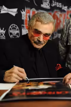 Burt Reynolds signs posters for Keesler personnel prior to the movie premiere of “Category 5” Oct. 22, 2014, at the Bay Breeze Event Center, Keesler Air Force B