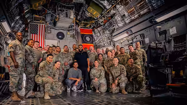 U.S. Airmen assigned to the 379th Air Expeditionary Wing pose for a group photo alongside actors Anthony Anderson and Nathan Anderson within the U.S. Central Co