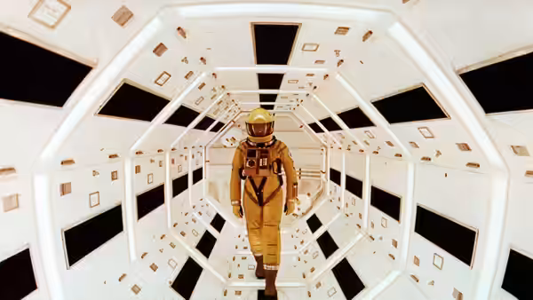An astronaut walking through the white cylindrical corridor of a space station