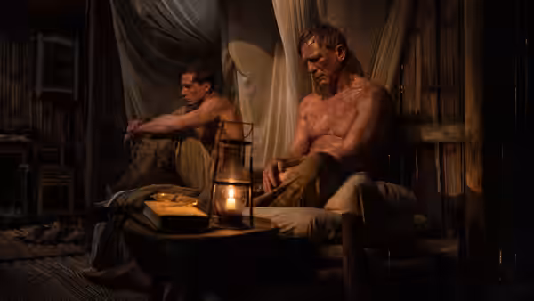 William Lee (Daniel Craig) and Eugene Allerton (Drew Starkey) sit shirtless in a wooden room