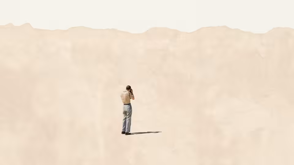 A man stands with his back to the camera in a vast empty landscape